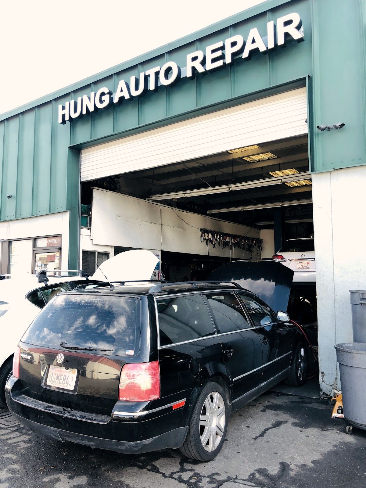 A wagon with the hood up at the Hung Auto bay door